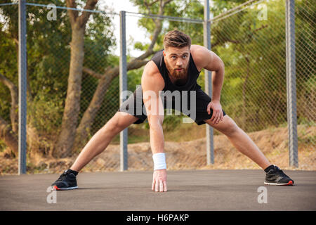 Zuversichtlich, dass junge Sportler dehnen und Aufwärmen vor dem Joggen im freien bärtigen Stockfoto