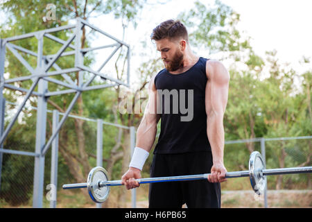 Überzeugt junge bärtige Fitness Mann Übungen mit der Langhantel im freien Stockfoto
