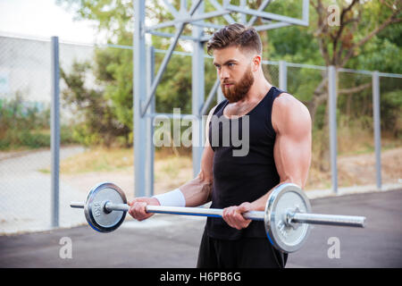 Überzeugt junge bärtige Fitness Mann Übungen mit der Langhantel im freien Stockfoto
