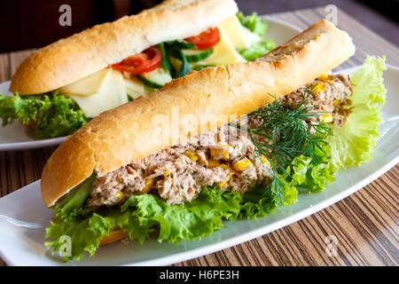 Thunfisch und Salat Baguette auf weißen Teller. Käse-Baguette im Hintergrund. Stockfoto