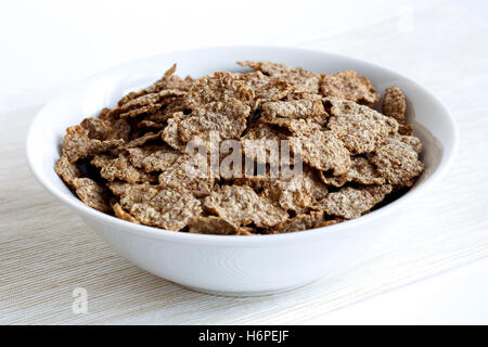 Weizen Kleie-Müsli mit keine Milch in eine Schüssel geben. Auf natürlichen Beige farbigen strukturierte Serviette. Auf weißem Hintergrund. Stockfoto