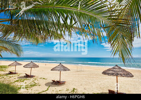 Liegestühle unter strohgedeckten Sonnenschirmen auf Lang Co Beach. Provinz Thua Thien Hue, Vietnam. Stockfoto
