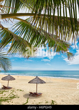 Liegestühle unter strohgedeckten Sonnenschirmen auf Lang Co Beach. Provinz Thua Thien Hue, Vietnam. Stockfoto