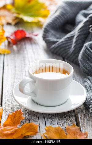 Tasse Tee mit Herbstlaub auf alten Holztisch. Stockfoto