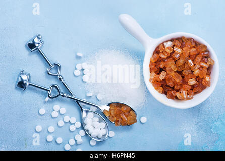 Haufen von Brown Sugar Cubes und Stevia auf blauem Hintergrund aus Holz Stockfoto