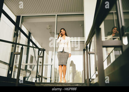 Business-Frau kommt die Treppe hinunter und reden über Handy Stockfoto