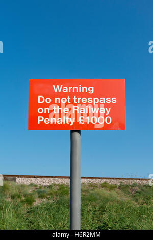 Rote Warnlampe nicht Schuld an der Bahnstrecke Strafe £1000 Zeichen auf der Pole mit Eisenbahnstrecke im Hintergrund gegen den klaren blauen Himmel Stockfoto