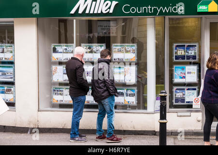 Personen, die Immobilieninformationen in einem Fenster für Immobilienmakler in einem Miller Countrywide Estate Agents in Falmouth, Cornwall, anzeigen. Stockfoto