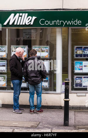 Zwei Personen, die Immobilien in einem Fenster von Miller Countrywide Estate Agents in Falmouth, Cornwall, betrachten. Stockfoto