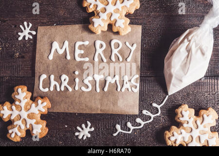 Weihnachten Lebkuchen, Inschrift und einen Beutel mit Puderzucker auf einem dunklen Hintergrund. Stockfoto