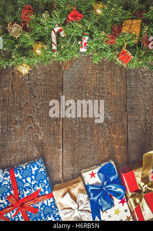 Weihnachtsgirlande mit Spielzeug und Geschenke auf einem dunklen Hintergrund aus Holz. Stockfoto