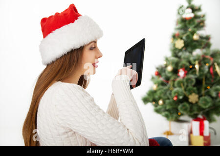 Frau sitzt mit Tablet-PC über Weihnachtsbaum Stockfoto