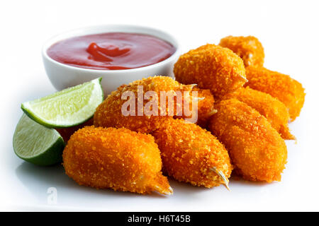 Haufen von gebratene panierte Surimi Krabben mit Schale mit Tomaten-Sauce und Zitrone Scheiben isoliert auf weiss. Stockfoto