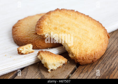 Zwei Butterkekse auf Serviette und Holz. Gebrochen. Stockfoto