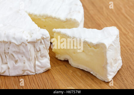 Scheibe Käse geschnitten aus eine große Runde auf eine Holzoberfläche. Stockfoto