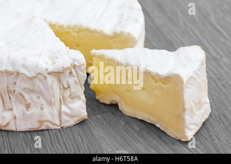 Scheibe Käse geschnitten aus eine große Runde auf eine Holzoberfläche. Stockfoto