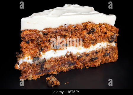 Stück Karottenkuchen mit reichen Zuckerguss. Isoliert auf schwarz. Stockfoto