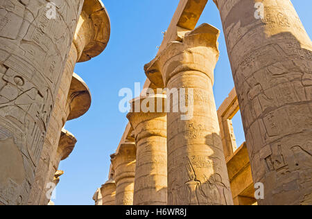 Die Zeilen der massiven Steinsäulen, bedeckt mit Reliefs mit antiken Hieroglyphen, Pharaonen und Götter in Hypostyle Halle von Karnak Stockfoto