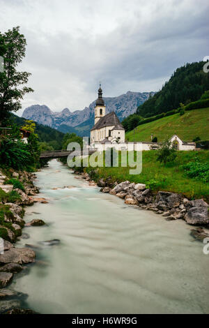 Die Kirche St. Sebastian, Fluss Ramsauer und alpine Berge im Hintergrund, Deutschland. Langzeitbelichtung Bild Stockfoto