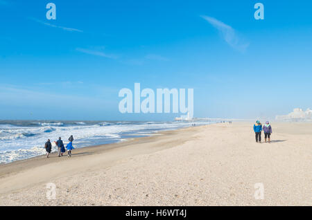 Nur wenige Menschen trotzen den heftigen Wind am Strand Nordsee mit dem Scheveningen Pier im Hintergrund Stockfoto