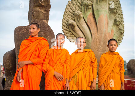 SIEM REAP, Kambodscha - 30. Oktober 2014: Anfänger buddhistische Mönche in orangefarbenen Gewändern posieren vor dem Eingang nach Angkor Wat. Stockfoto