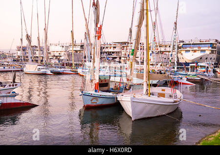 Die alten traditionellen Feluken sind mit den großen Kreuzfahrtschiffen im Hafen am Nil, Luxor benachbarten. Stockfoto