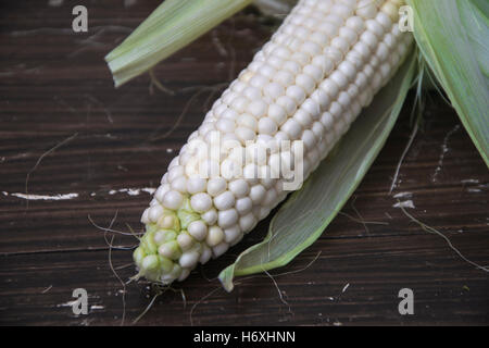 Frischer Mais auf Maiskolben auf rustikalen Holztisch Stockfoto