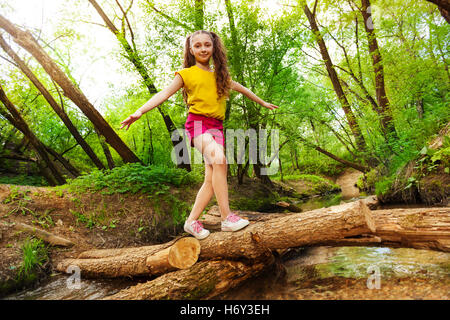 Junges Mädchen, balancieren auf einem Protokoll-Crossing-Over-Fluss Stockfoto