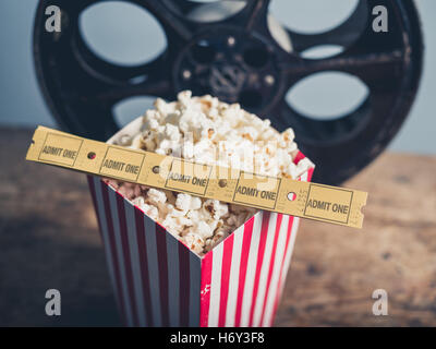 Kino-Konzept der alten Filmrolle mit Popcorn und Film-Tickets auf einer Holzoberfläche Stockfoto
