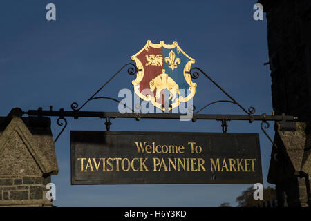 Melden Sie mit dem Tavistock-Wappen über dem Eingang zum Pannier Markt neben der Guildhall, mit blauem Himmel hinter Stockfoto