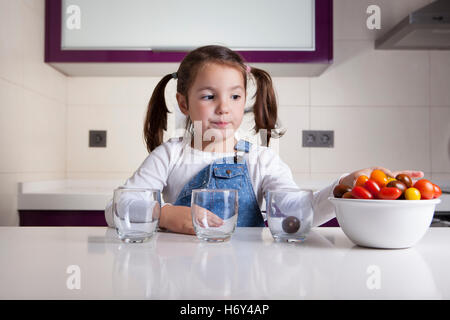 Kleines Mädchen Sortierung nach Farben Cherry-Tomaten. Aufklärung über gesunde Ernährung für Kinder Stockfoto