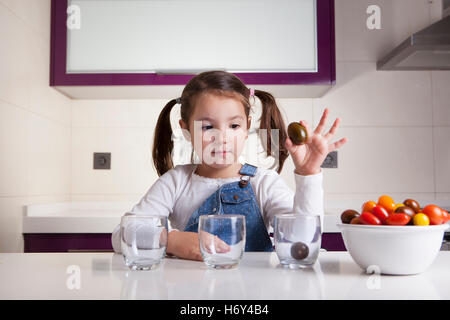 Kleines Mädchen Sortierung nach Farben Cherry-Tomaten. Aufklärung über gesunde Ernährung für Kinder Stockfoto