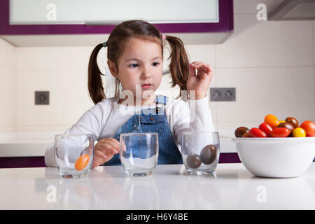 Kleines Mädchen Sortierung nach Farben Cherry-Tomaten. Aufklärung über gesunde Ernährung für Kinder Stockfoto