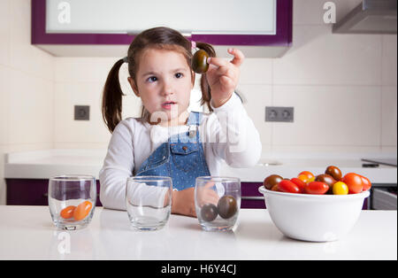 Kleines Mädchen Sortierung nach Farben Cherry-Tomaten. Aufklärung über gesunde Ernährung für Kinder Stockfoto