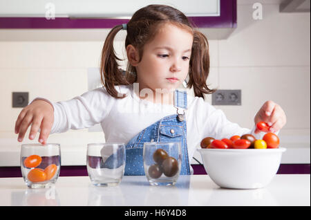 Kleines Mädchen Sortierung nach Farben Cherry-Tomaten. Aufklärung über gesunde Ernährung für Kinder Stockfoto