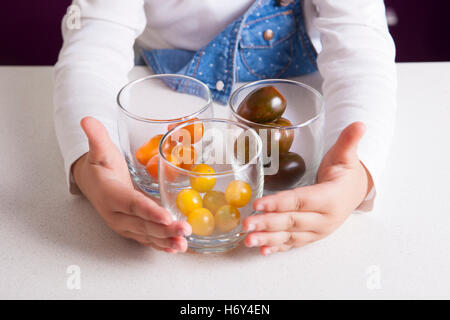 Kleines Mädchen Sortierung nach Farben Cherry-Tomaten. Aufklärung über gesunde Ernährung für Kinder Stockfoto