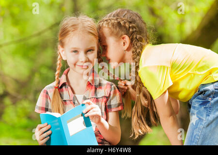 Zwei kleine Mädchen Geheimnisse ins Ohr flüstern Stockfoto
