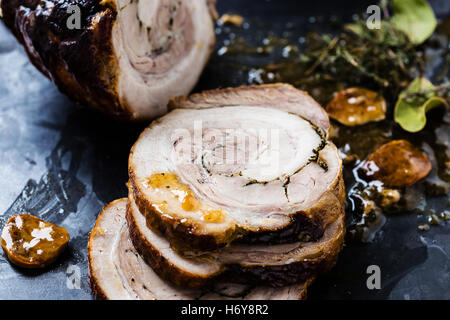 In Scheiben geschnittenen Braten Roll gefüllt mit Kräutern auf einem grauen Brett Stockfoto