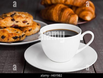 Tasse Kaffee mit frischem Gebäck und Croissants auf Holztisch Stockfoto