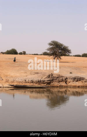 Afrikanerin und Einbaum in einem Landschaft an den Ufern des Flusses Niger in Mali, Afrika Stockfoto