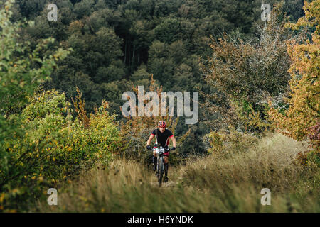 männliche Fahrradfahrer bergauf zwischen Wäldern und Rasen während Krim Rennen mountainbike Stockfoto