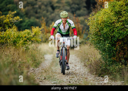 männliche Fahrradfahrer bergauf auf einem Bergweg mit Lächeln im Gesicht während der Krim Rennen mountainbike Stockfoto