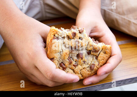 Kind hält große halb gegessen mit hausgemachten Schokosplittern. Stockfoto