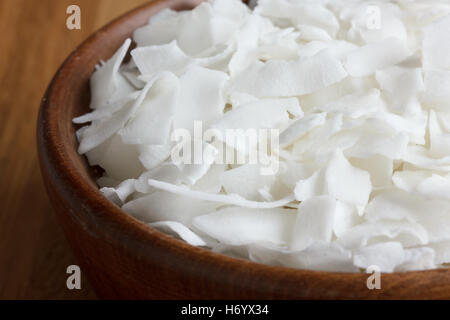 Dunkles Holz Schüssel rasierte Kokosnuss auf Holztisch. Stockfoto