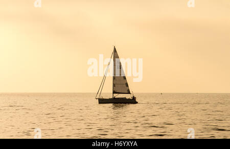 Segelyacht beleuchtet von der Sonne und die Sonne an der Adria am Nachmittag an einem bewölkten Tag in der Stadt Piran, Slowenien. Stockfoto