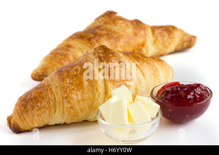 Zwei Croissants auf einer weißen Fläche mit Butter und Marmelade. Stockfoto