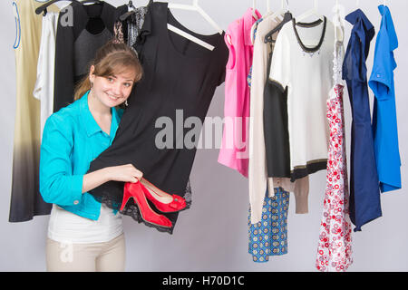 Ein junges Mädchen, hob das Kleid zu den roten hochhackigen Schuhen nachdenklich wählt Kleidung im Kleiderschrank Stockfoto