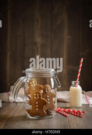 Lebkuchenmänner in Cookie jar mit Milch und Strohhalme im Hintergrund Stockfoto