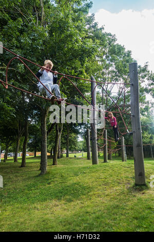 Zwei junge, im Alter von sieben Jahren, Kinder spielen in einem öffentlichen Park auf einem Klettergerüst im Vereinigten Königreich. Stockfoto