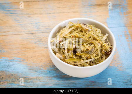 eine kleine Keramikschale Seetang Salat basierend auf Agar-agar gegen Grunge Holz Stockfoto